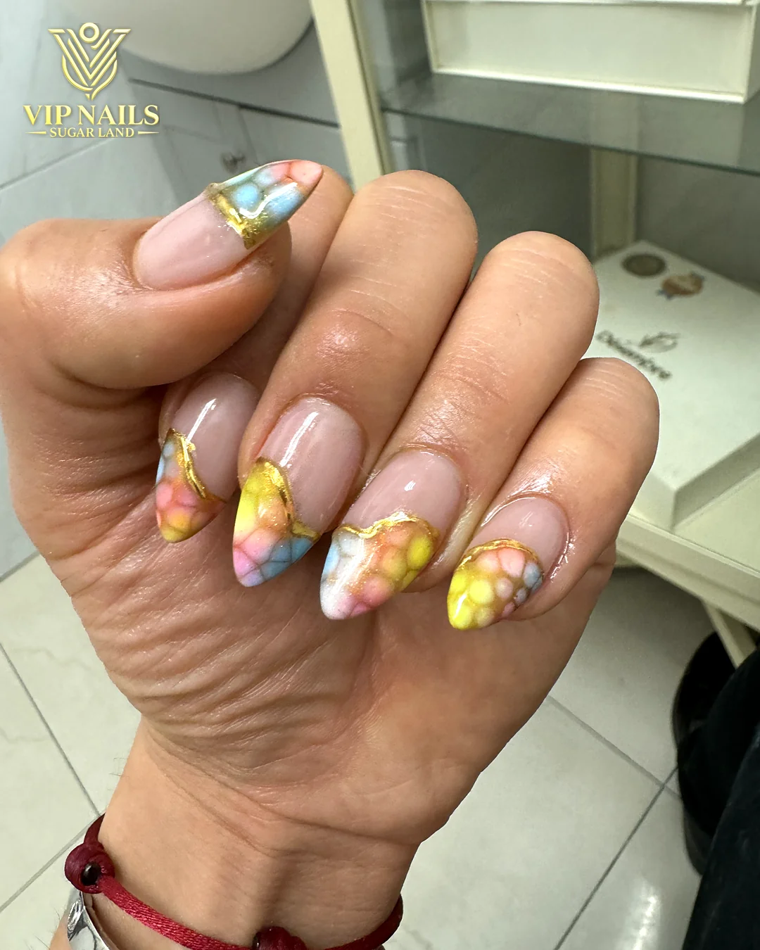 Medium almond nails with hand-painted yellow and pastel art by VIP Nails Sugar Land